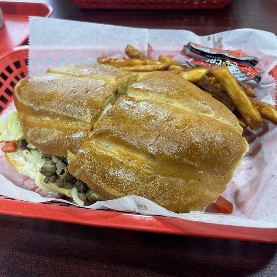 A Sazón Bello Taquería torta with fries and ketchup packets in a red basket.
